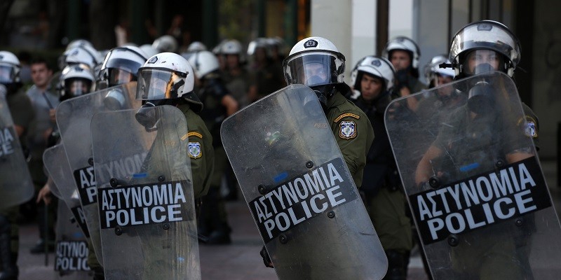 Riot police guard near an anti-austerity protest in Athens, Wednesday, July 15, 2015. Greece has a tentative rescue deal, but relief that it is not falling out of the euro is unlikely to last long: its economy has taken a huge hit. Months of political brinkmanship, uncertainty and bank closures have hurt companies and brought everyday business to a standstill. (AP Photo/Emilio Morenatti)
