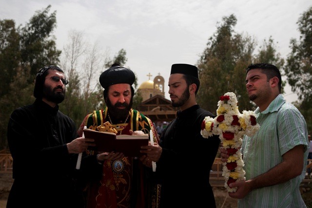 Syrian Orthodox priests hold baptism ceremonies on the Israeli side of the Jordan river at Qasr el-Yehud, near Jericho during the holy week of Easter. Qasr el-Yehud is believed to be the place where Jesus was baptized. Several hundreds of christian orthodox pilgrims from around the world attended services by the river during celebrations of the Orthodox Easter holiday, but were prevented by Israeli police from descending into the muddy banks of the Jordan River due to safety concerns. April 14, 2009. Photo by Matanya Tausig/Flash 90 *** Local Caption *** צליינים טבילה ירדן קסר אל יהוד נצרות דת